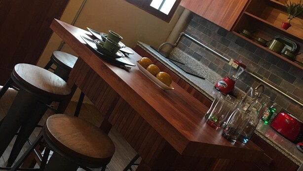 A compact kitchen with a wooden island, bar stools, a window, and a stone backsplash. - Loft In Merida For Five (Mérida)