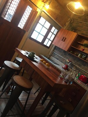A compact kitchen with a wooden island, bar stools, a window, and a stone backsplash. - Loft In Merida For Five (Mérida)