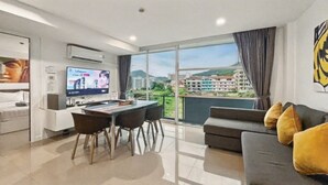 Un salon moderne avec balcon, un téléviseur à écran plat et un coin repas.