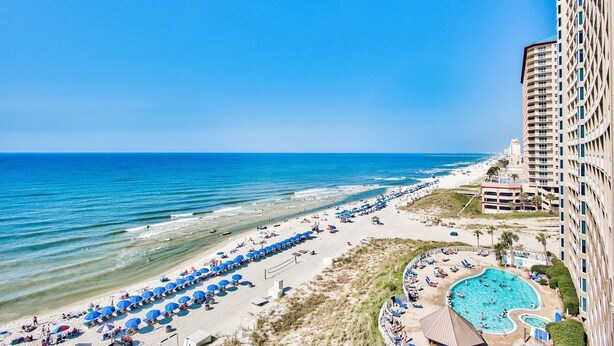 Un hotel vacacional a la platja amb piscina, ombrelles i vista a l'oceà.