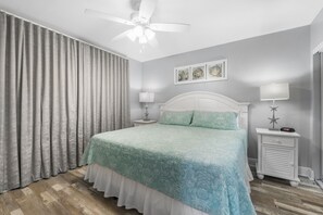 Relax in this serene bedroom with a large bed, two bedside tables, and a ceiling fan.