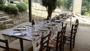 Een lange eettafel buiten opgesteld, met stoelen, een fles wijn en lege borden.