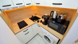 A compact kitchen with a sink, stove, toaster, coffee maker, and washing machine. - Park Studio Cismigiu Gardens - Quiet Room - Smart Tv (Bucharest)