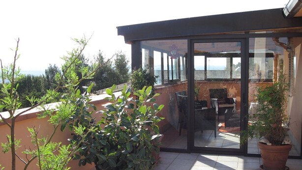 A rooftop terrace with potted plants, a glass door leading to an outdoor seating area, and a view of the sea. - A Relaxing Holiday, Even With Your Four-legged Friends (Avola)