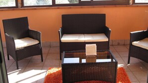 A room with three wicker chairs and a sofa, a small table, and a window with a view of greenery. - A Relaxing Holiday, Even With Your Four-legged Friends (Avola)