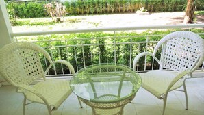 Un balcon avec deux fauteuils en osier et une table en verre.