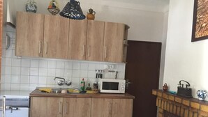 Een compacte keuken met houten kastjes, een magnetron en een klein spoelbakje.
