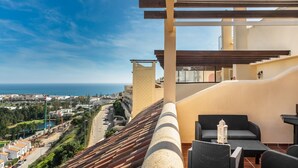 Ein Balkon mit Meerblick, Gartenmöbel und einem Baukran im Hintergrund.