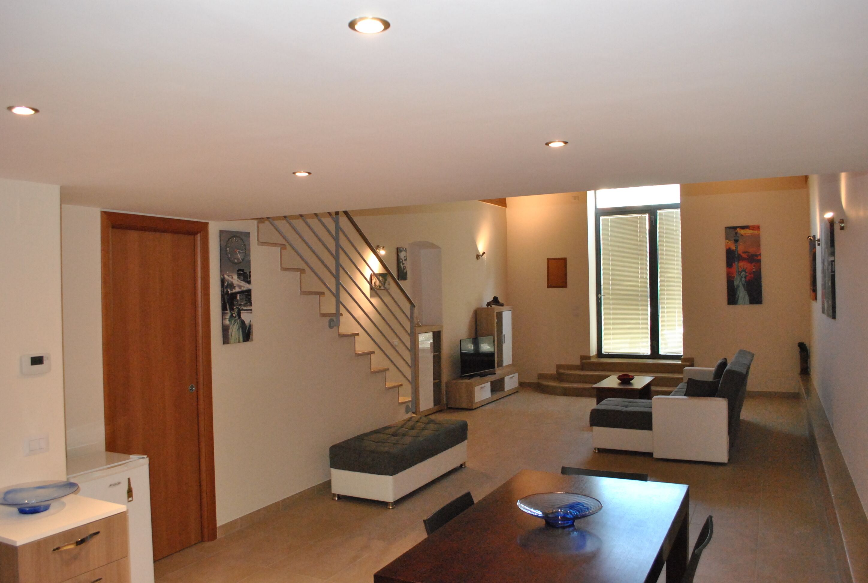 A modern living room with a staircase, a dining area, and a seating area.