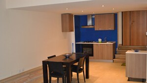 A modern kitchen with wooden cabinets, a dining table with chairs, and a blue accent wall. - Corona Matera Holiday Home (Matera)
