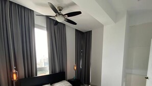 A modern bedroom with a bed, a ceiling fan, and a nightstand with a lamp. - Apartment Of 1 Bedroom Plus Study With Sofa Bed (Santo Domingo)
