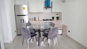 A modern kitchen with white cabinets, a stainless steel refrigerator, a gas stove, and a water dispenser. - Apartment Of 1 Bedroom Plus Study With Sofa Bed (Santo Domingo)