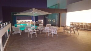 A poolside area with lounge chairs and tables, a large umbrella, and a view of the pool. - Apartment Of 1 Bedroom Plus Study With Sofa Bed (Santo Domingo)