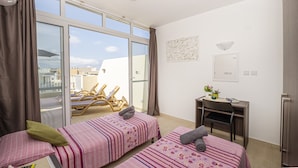 A room with two beds, a desk, and a view of the city. - Summer Breeze Penthouse With Hot Tub (Mellieha)