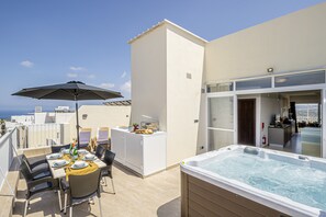 A rooftop terrace with a dining table, chairs, a hot tub, and a kitchen area. - Summer Breeze Penthouse With Hot Tub (Mellieha)