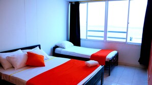 Ett hotellrum med två sängar, den ena med ett rött överkast och den andra med ett vitt överkast.