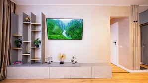 Ein modernes Wohnzimmer mit einem großen Flachbildfernseher an der Wand, einer eingebauten Bücherwand und einem kleinen Tisch mit Dekoration.