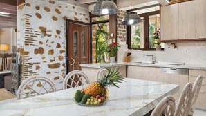 A kitchen with a marble island, white chairs, and a fruit bowl. - Villa Splantzia-heated Pool-garden-2 min Chania Port (Chania)