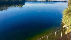 Een rustige rivier met een houten terras en balustrade aan de rechterkant.