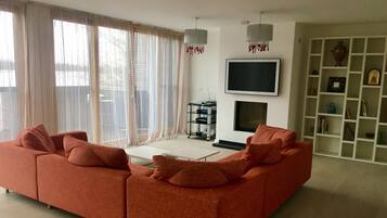 A modern living room with a sectional sofa, a flat-screen TV, and a fireplace.