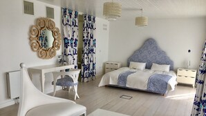 Een slaapkamer met een bed, nachtkastjes, een stoel, een bureau en gordijnen.