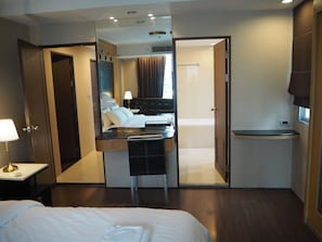 A hotel room with a bed, a desk, a mirror, a bathroom, and a window. - Custom Design Loft With City Views And Rooftop Pool (Bangkok)