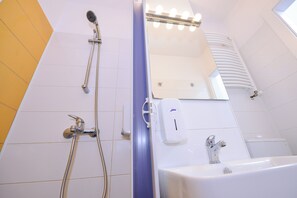 Een badkamer met een douche, wastafel en een spiegel met verlichting.