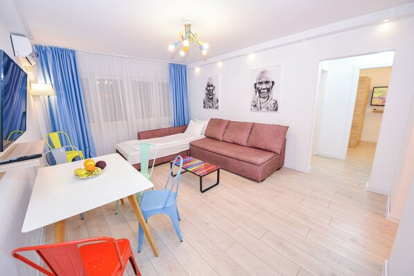 Een moderne woonkamer met een witte tafel, kleurrijke stoelen, een bruine bank en een kleine salontafel.
