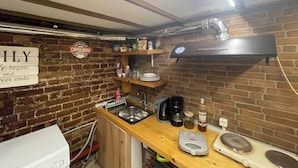 Une cuisine avec un mur en briques, un panneau publicitaire pour le café, un évier et une machine à café.