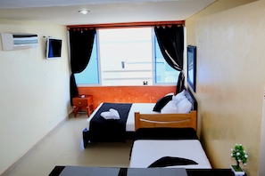 A hotel room with two beds, a small table, an air conditioner, a TV, and a window with curtains. - Loft sea View 19C air and Wifi (Cartagena)