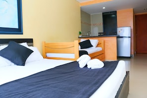 A hotel room with two beds, a kitchenette, and a bathroom.