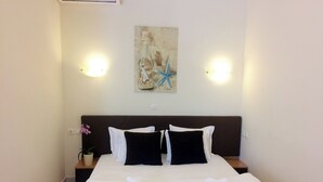 Habitació d'hotel amb un llit, dues taules de nit, una estantària, una planta en test i una obra d'art penjada a la paret.