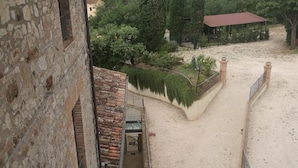 A stone building with a balcony overlooking a sandy area with a fence and greenery. - Apartment Iris 3 Bedrooms,2 Bath, Living Room 10 Pax (Monte Castello di Vibio)