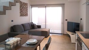 A modern living space with a dining area, a sofa, a TV, and a kitchen. - Private Roof w Plunge Pool, Brand New 2 Br Penthouse for 6 Sleeps! (Tulum)