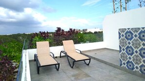 A rooftop terrace with two lounge chairs, a view of the city, and a patterned wall. - Private Roof w Plunge Pool, Brand New 2 Br Penthouse for 6 Sleeps! (Tulum)