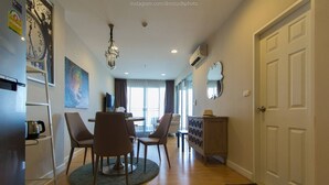 A modern living room with a dining area, wooden flooring, a chandelier, and a large clock on the wall. - Seaview 2 Brs With Chicz Furniture Hua Hin Beach 3 (Cha-am)