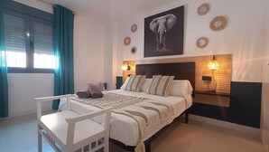 A bedroom with a bed, bedside tables, a chair, a large elephant painting, and wall decor. - 88 - Livingtarifa La Marea (Tarifa)
