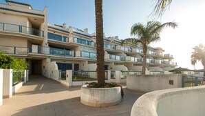 A multi-story hotel with balconies, a central courtyard, and palm trees. - 88 - Livingtarifa La Marea (Tarifa)