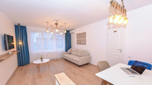 Een moderne woonkamer met een bank, een eettafel en een laptop op de tafel.
