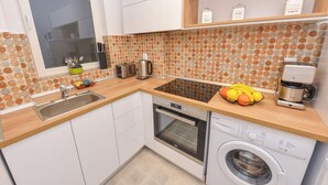 Een kleine keuken met een inbouwoven, een wasmachine en een raam met uitzicht.