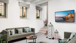 A living room with a sofa, a coffee table, a TV, and a staircase. - Boutique Home-splantzia- Roof Garden-2min Chania Harbor (Chania)