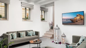 A living room with a sofa, a coffee table, a TV, and a staircase. - Boutique Home-splantzia- Roof Garden-2min Chania Harbor (Chania)