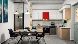 A modern kitchen with a dining area, stainless steel appliances, and a red accent wall. - Boutique Home-splantzia- Roof Garden-2min Chania Harbor (Chania)
