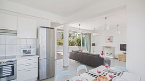 Une cuisine moderne avec un coin repas, des appareils en acier inoxydable et une grande fenêtre donnant sur un jardin.
