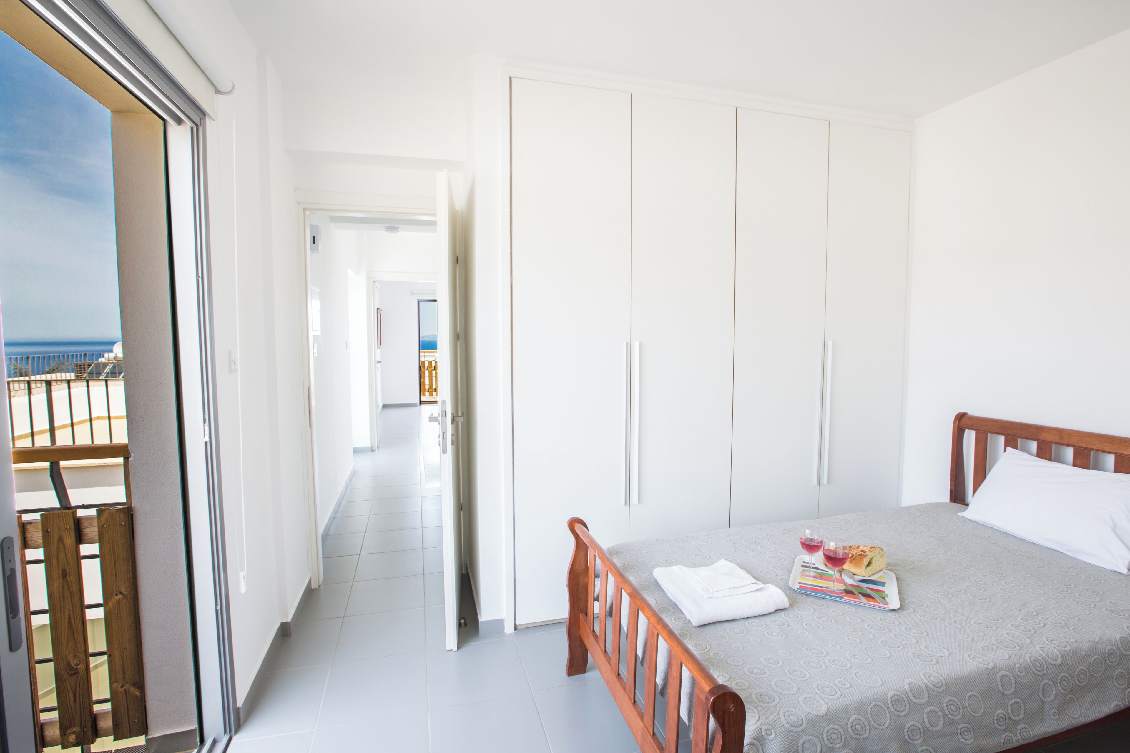 A hotel room with a balcony, a bed with a magazine, and a view of the sea.