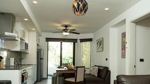 A modern kitchen with a dining area, a ceiling fan, and large windows. - Classy 2 Br Apartment Fully Equipped, Up To 5 People, at Aldea Zama (Tulum)