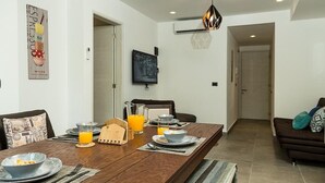 A dining area with a wooden table set for breakfast, a coffee maker, and a pitcher of orange juice. - Classy 2 Br Apartment Fully Equipped, Up To 5 People, at Aldea Zama (Tulum)