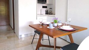 Een moderne keuken met een magnetron, koffiezetapparaat en blender. Er staat een eettafel gedekt met borden, kopjes en bestek.