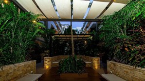 An indoor garden with stone planters, benches, and a central water feature. - Studio Close to 5th Av, With Amazing Roof Pool View, Gym, Spa and More! (Playa del Carmen)