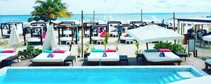 A beach resort with a pool area, lounge chairs, and umbrellas. - Studio Close to 5th Av, With Amazing Roof Pool View, Gym, Spa and More! (Playa del Carmen)